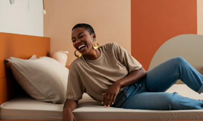 black woman in her mid 30s smiling while sitting on her bed in newly remodeled bedroom